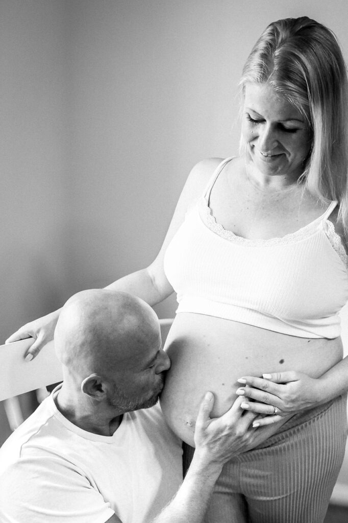 Dasselbe Foto in Schwarzweiß: Der werdende Papa darf beim Babybauchshooting gerne eine Rolle spielen. Ob als helfende Hand im Hintergrund oder als Fotopartner vor der Kamera.